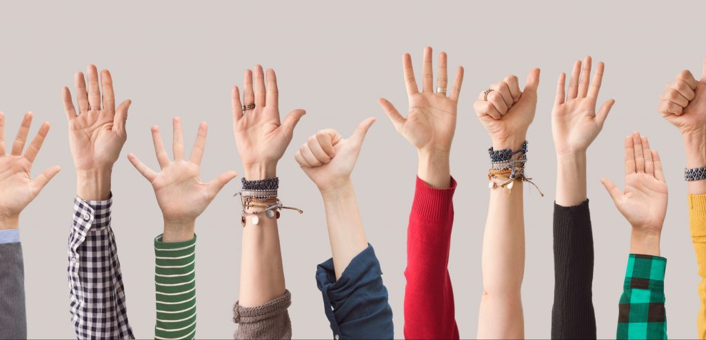 Imagen de portada de sección "Qué hacemos" en donde se observan personas levantando sus manos