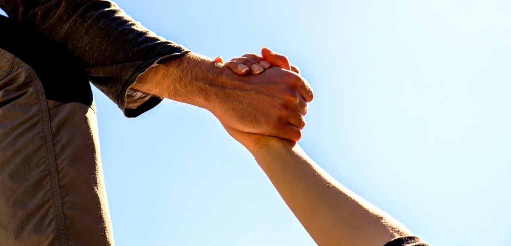 Imagen de portada de sección "Impacto social" en donde se visualiza una mano agarrando y levantando la de otra persona