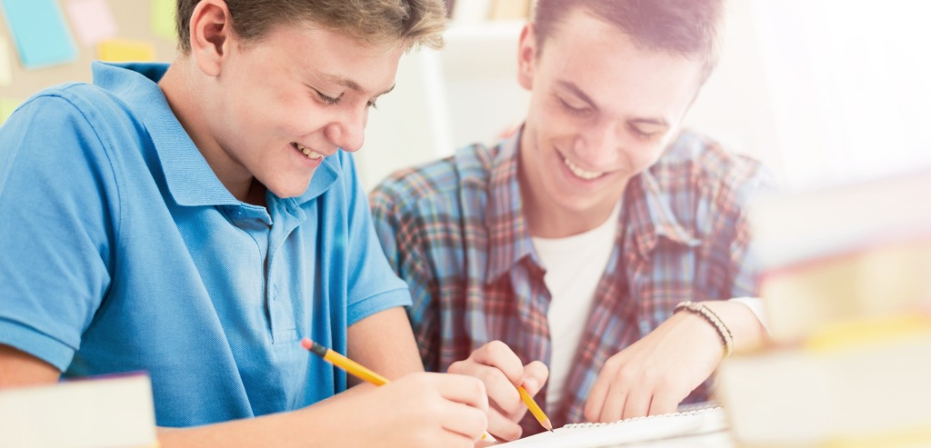 Imagen de portada de sección "Modelo Educativo" - Se visualizan dos jóvenes sonriendo y escribiendo en papel